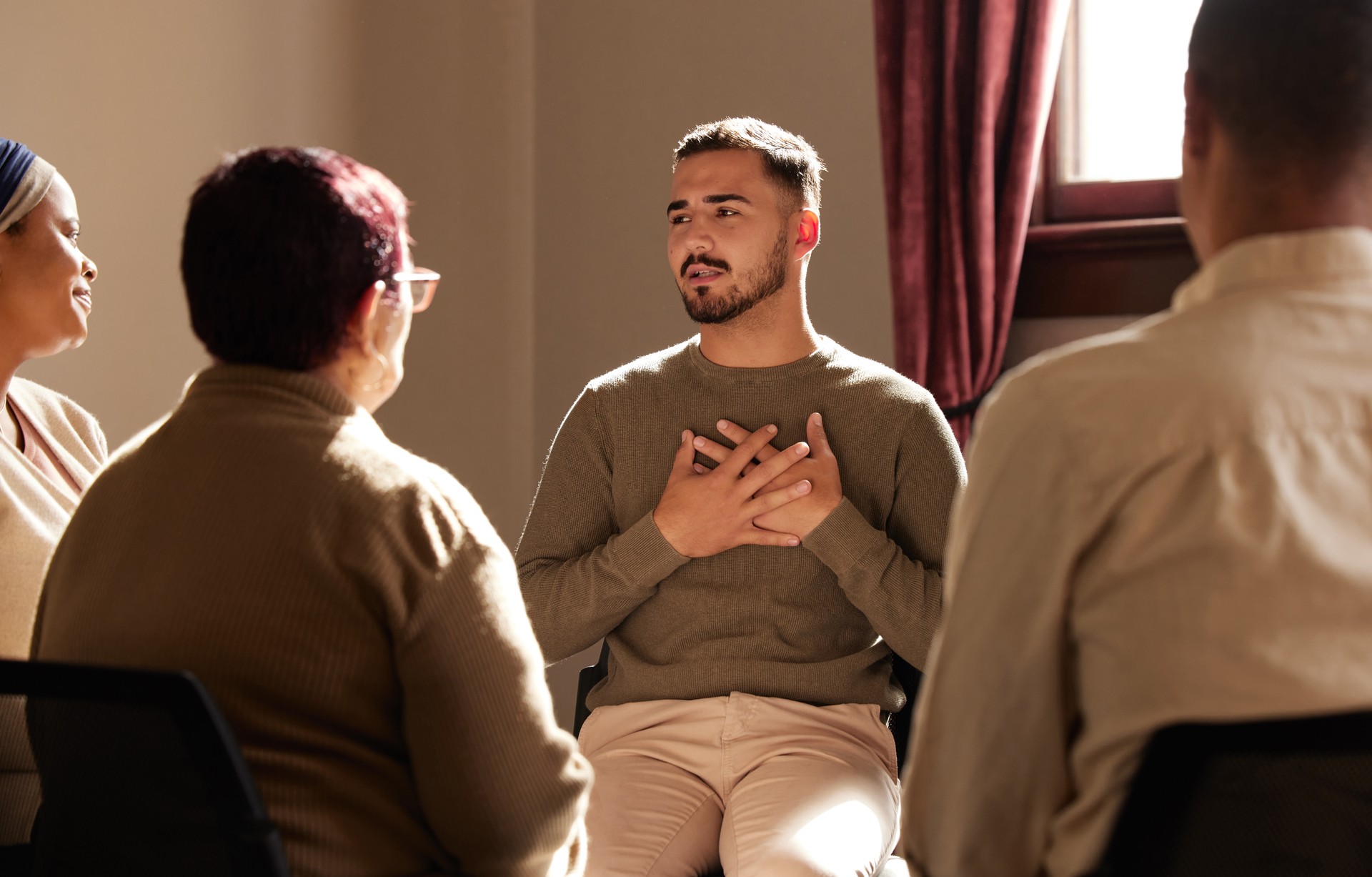 Support, trust and man sharing in group therapy with understanding, feelings and talking in session. Mental health, addiction or depression, men and women with therapist sitting together for healing.